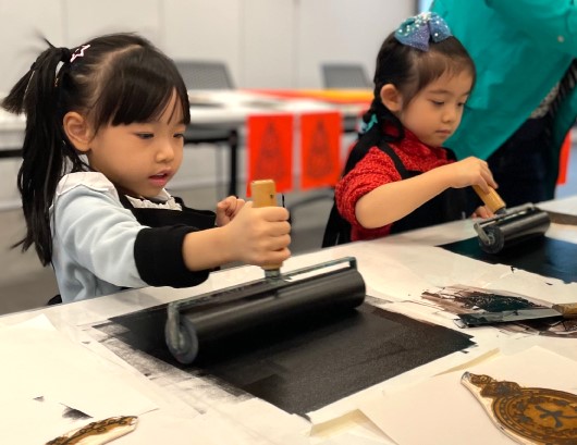 Participants use ink rollers to colour printing plates.
