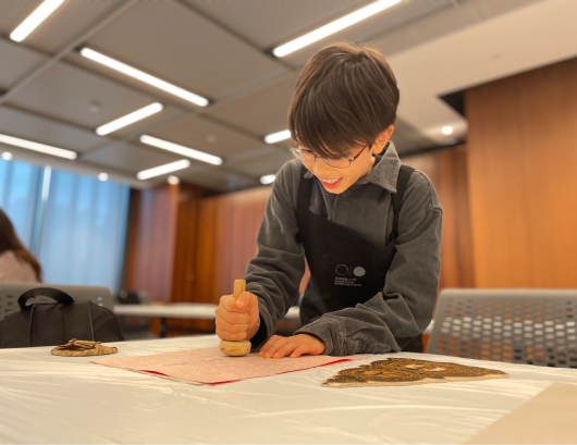 Participant unleashes creativity using a wooden mushroom tool to experience woodblock printmaking.
